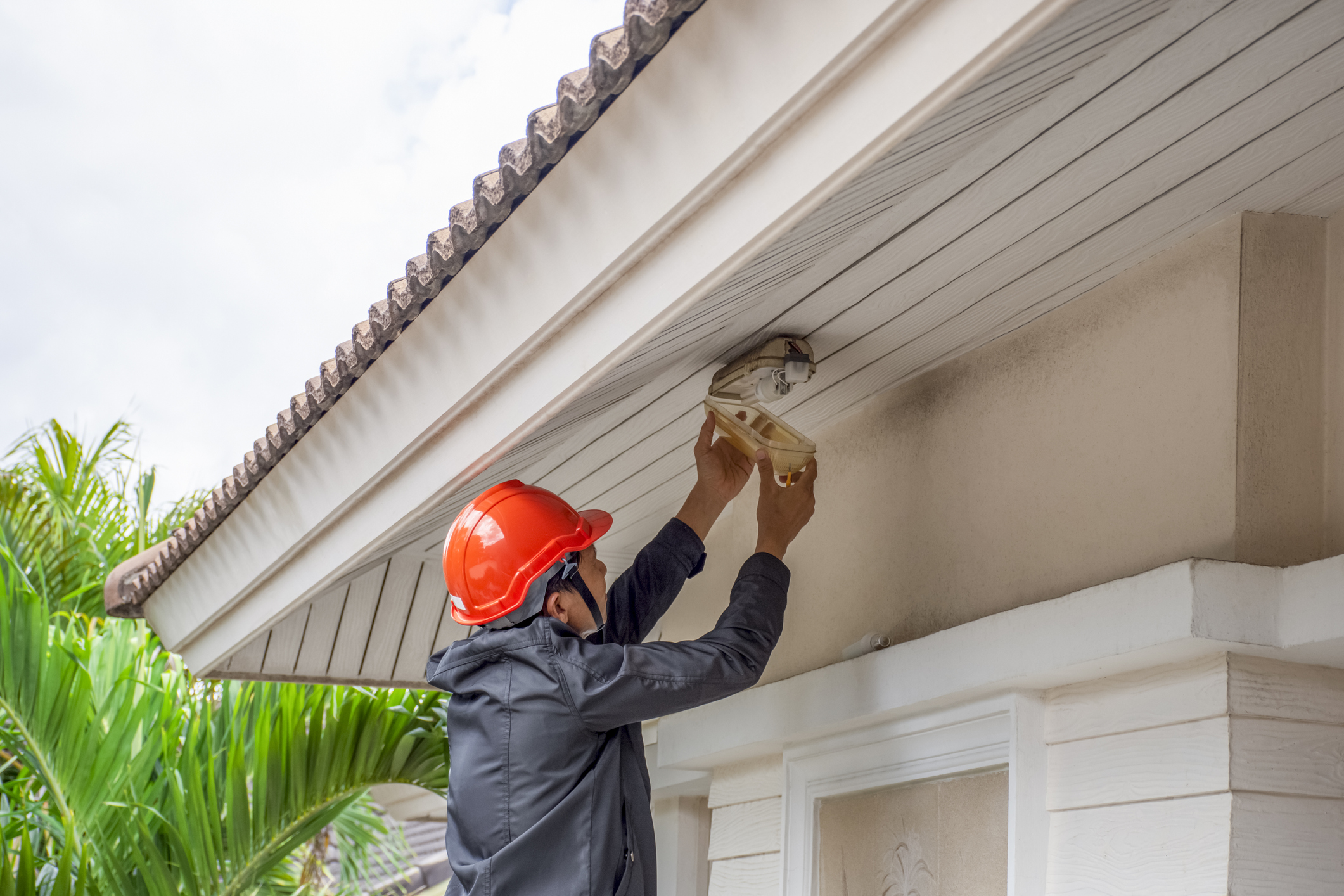 Electrician man working on exterior light, install LED replacement lamp at home