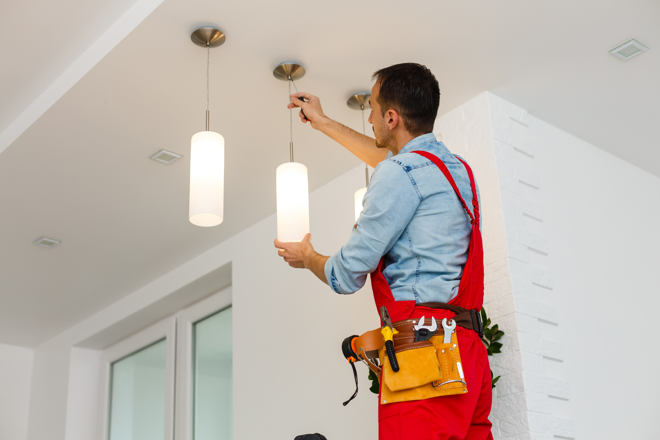 Electrician man worker installing ceiling lamp