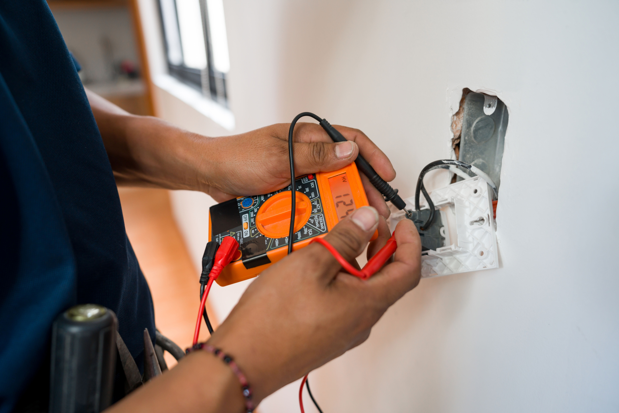 electrician fixing an electrical outlet and measuring the voltage at a house